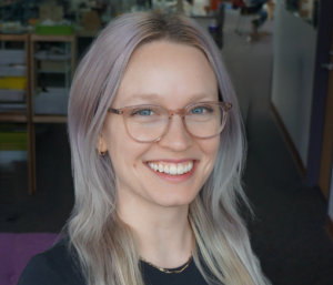 Yasmine Kotturi's headshot with purple hair and pink glasses.